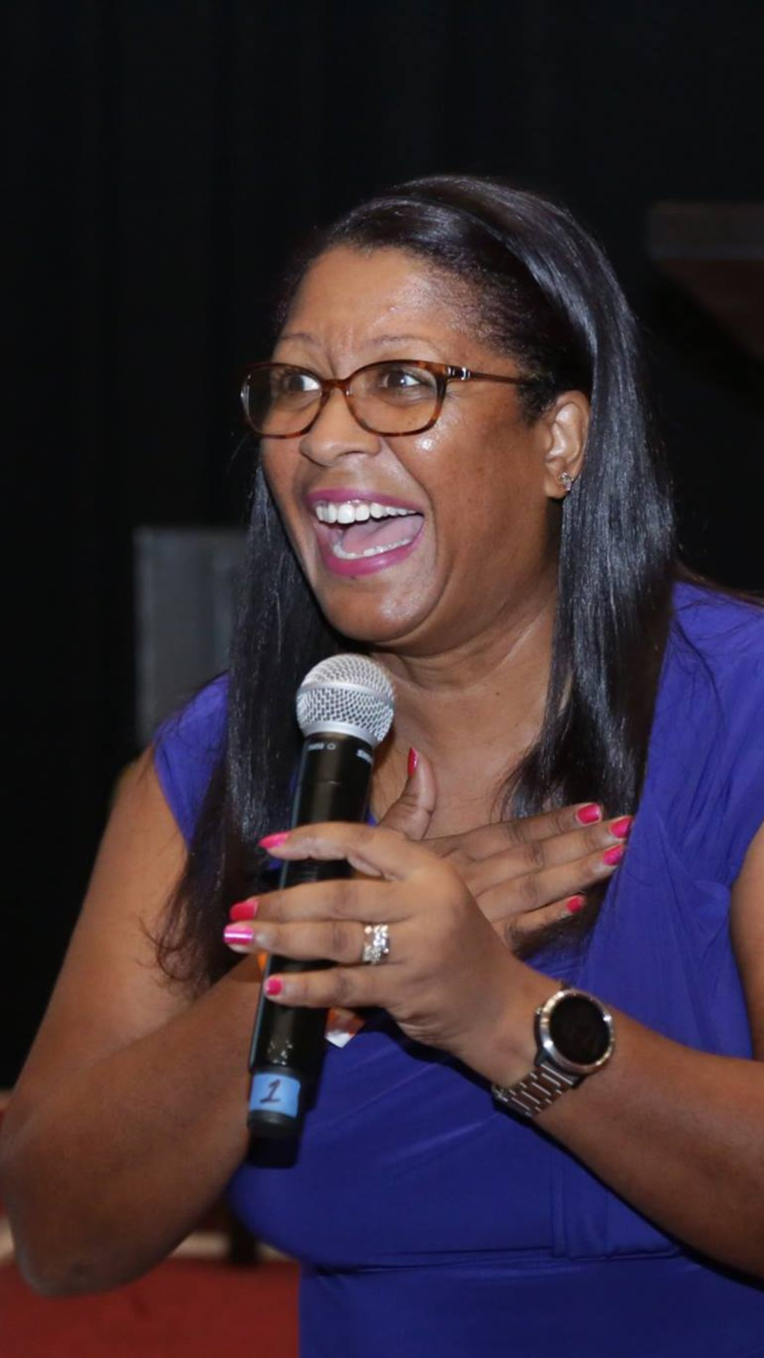 smiling woman holding and speaking into a microphone 
